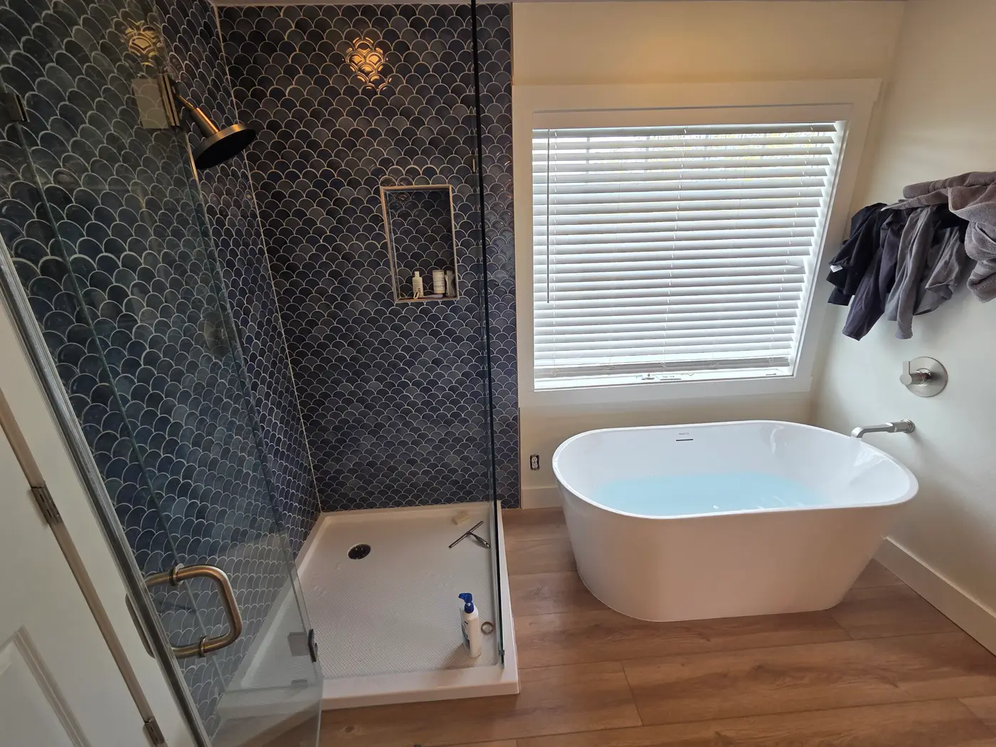 Finished bathroom remodel by Revolution Plumbing with a tiled walk-in shower and freestanding tub