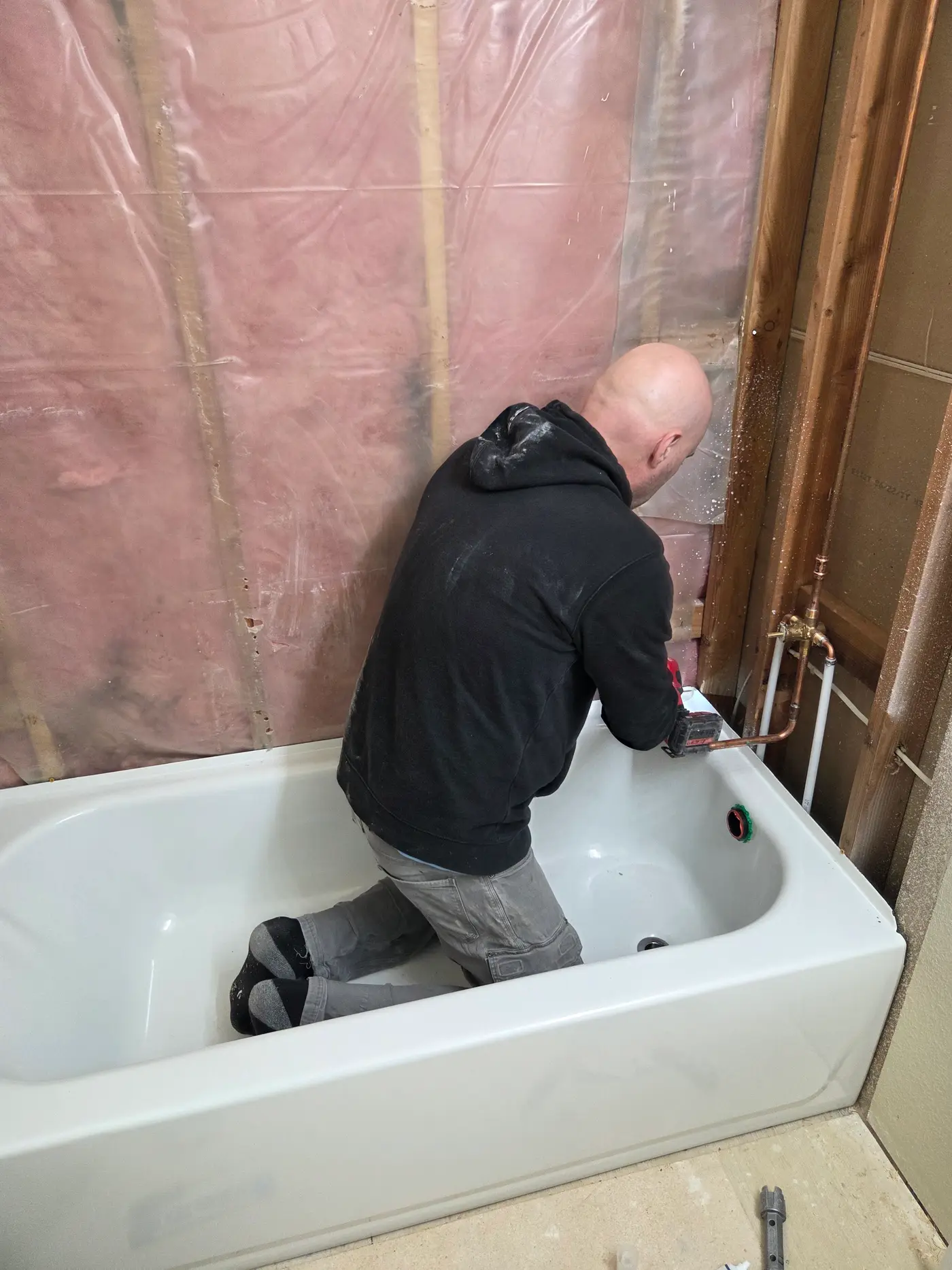 David from Revolution Plumbing setting plumbing connections during a bathroom job