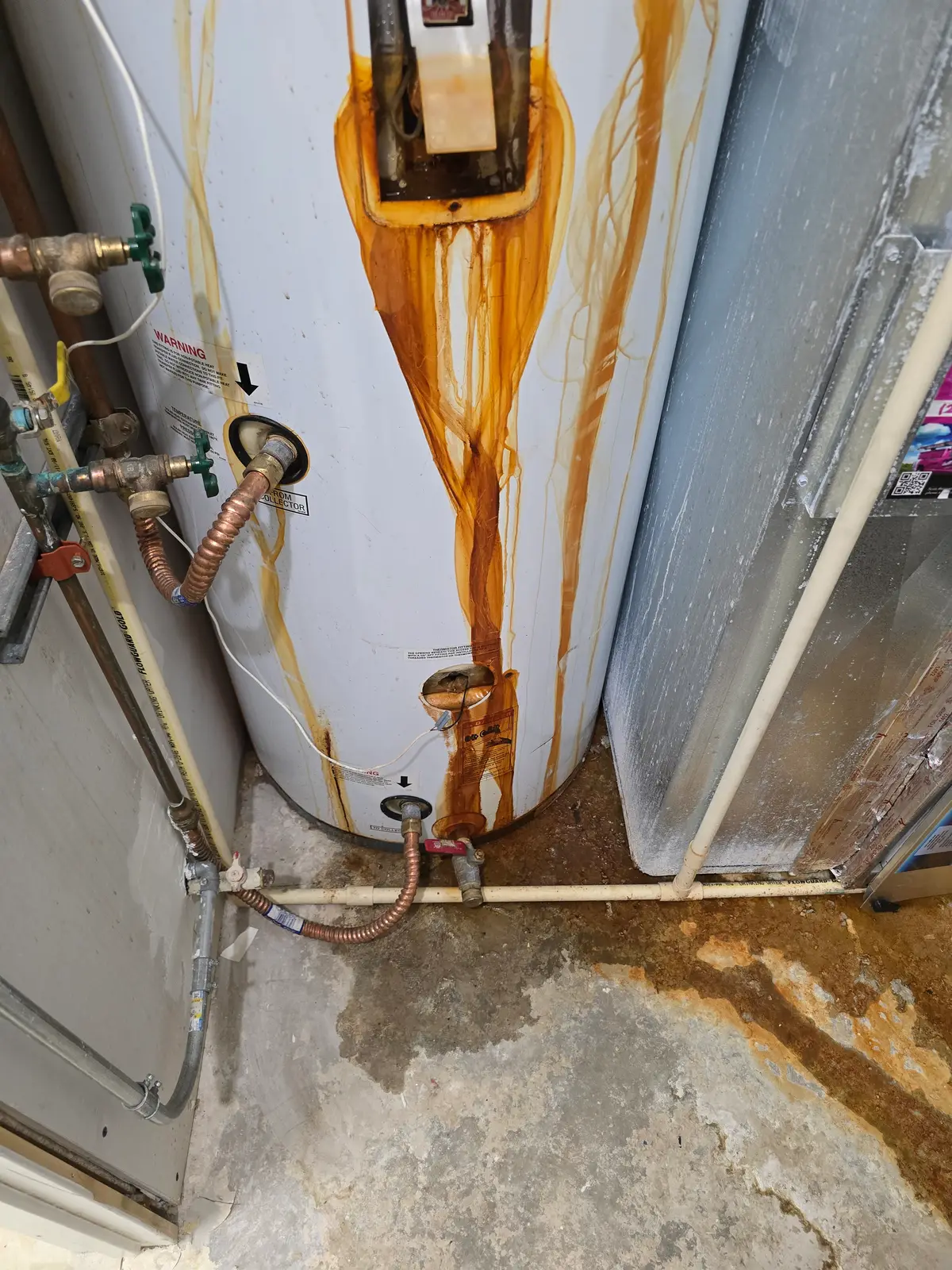 A failed, rust-streaked water heater leaking in a Treasure Valley home before emergency replacement by Revolution Plumbing
